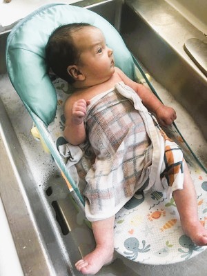 Baby in the bath with a towel on his belly.