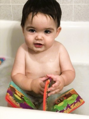 Baby in the bath with a bath book.