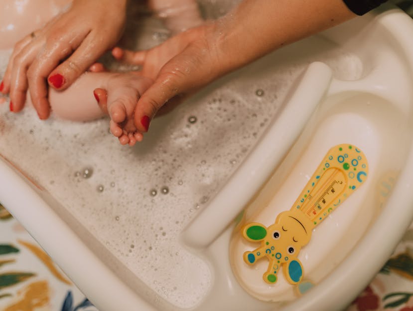 A caring parent gently bathes a baby in a bubbly bathroom scene, showcasing love and hygiene.