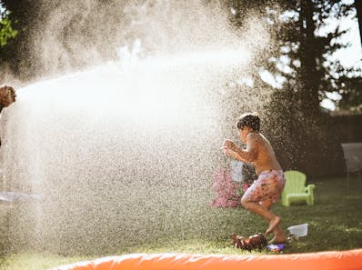 Boy enjoying water spray in backyard on a sunny summer day, capturing fun and joy.