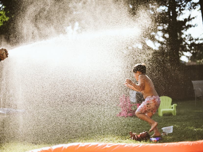 Boy enjoying water spray in backyard on a sunny summer day, capturing fun and joy.