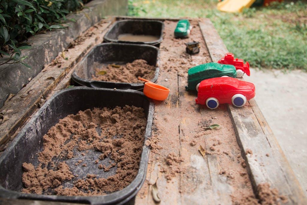 Toy cars in a sandy play area create a fun outdoor scene.
