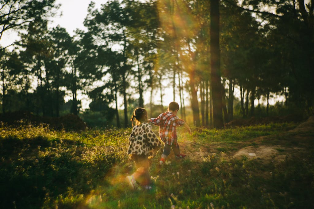 Two children running through a sunlit forest during the golden hour, capturing the spirit of adventure and play.
