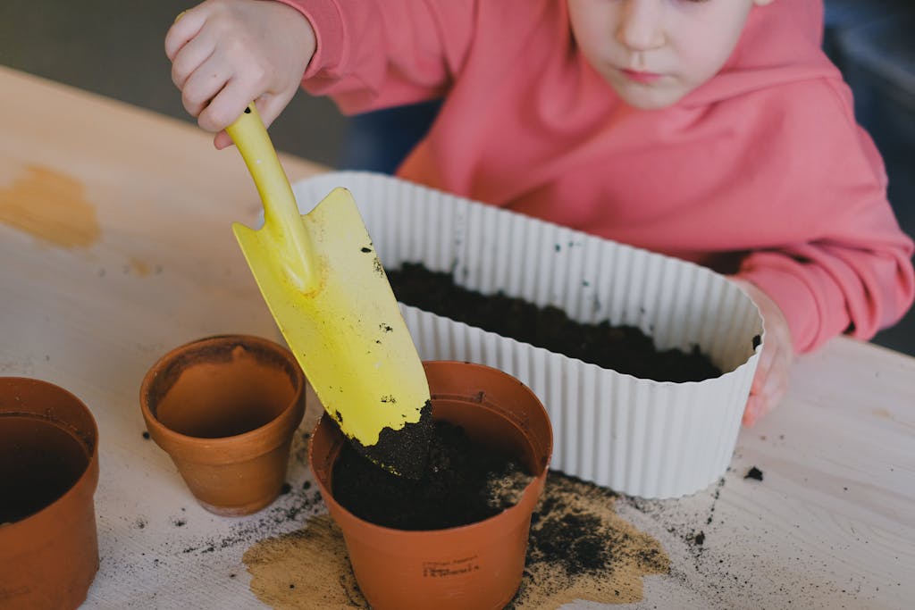Young child engaged in planting using clay pots and soil, learning gardening basics.